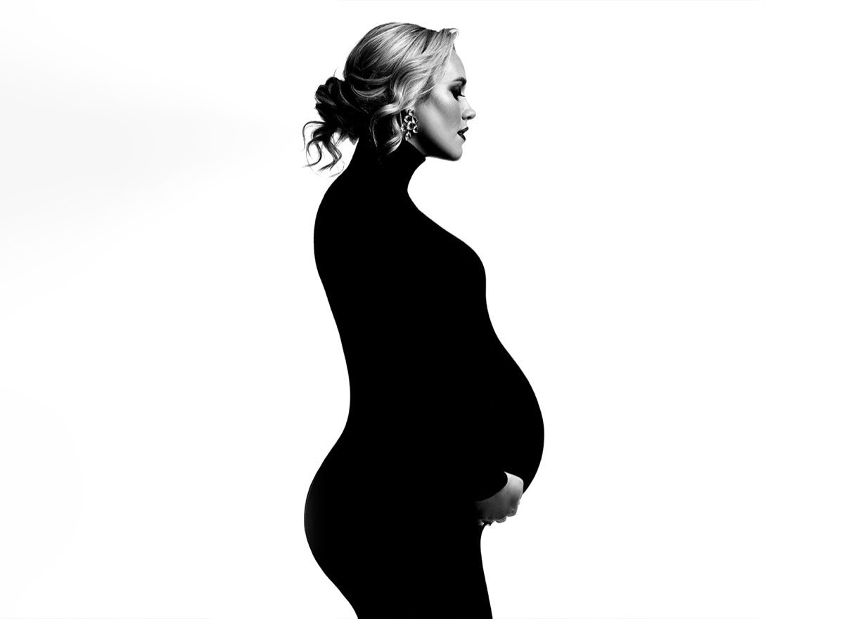 Black-and-white maternity silhouette portrait in a fitted black dress